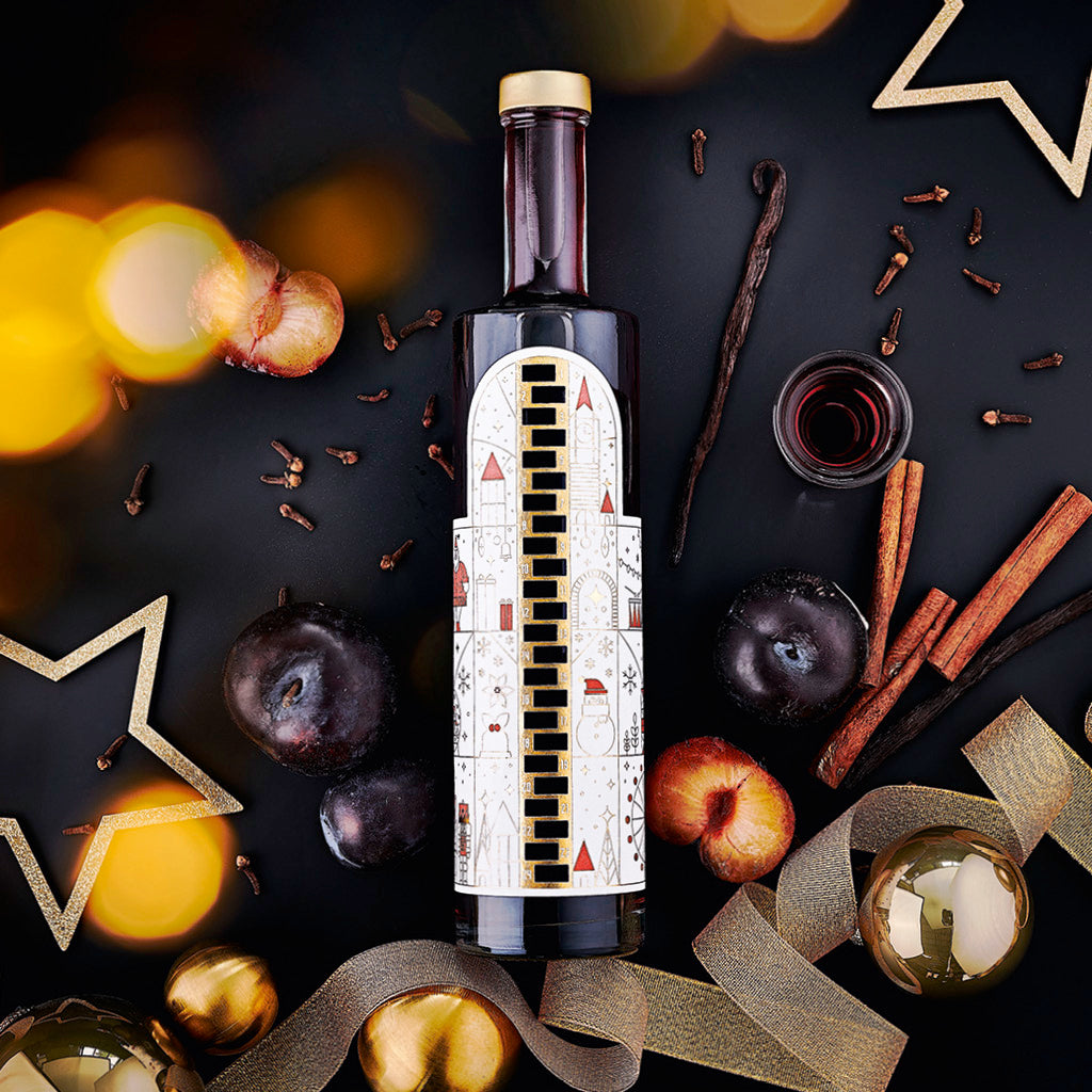 Wajos Adventskalender Flasche gefüllt mit Gewürzpflaumen Likör dargestellt mit weihnachtlicher Deko