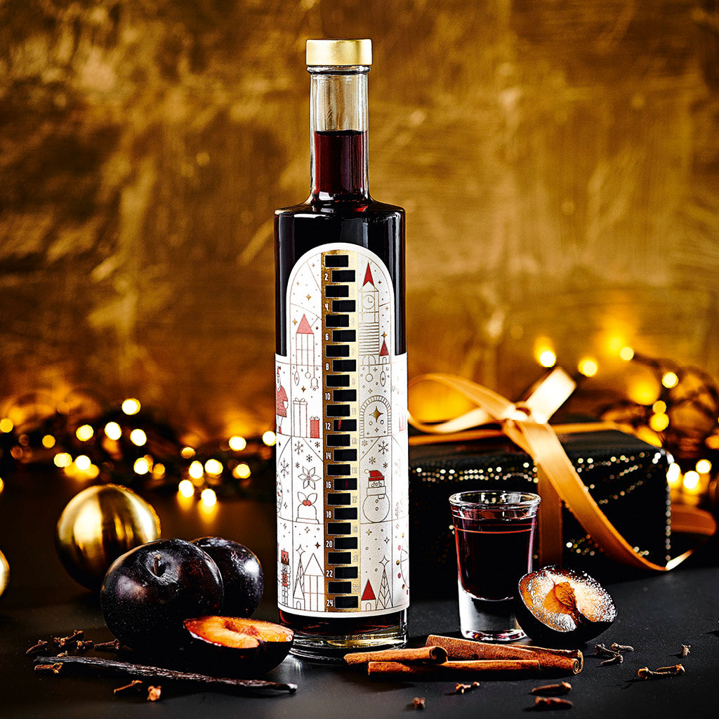 Wajos Adventskalender Flasche gefüllt mit Gewürzpflaumen Likör dargestellt mit Shot Glas
